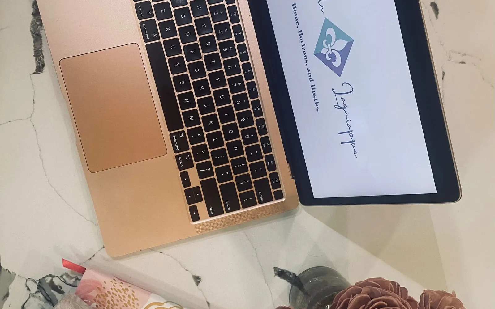 A laptop, a journal, and an elegant pen laid out on a marble surface